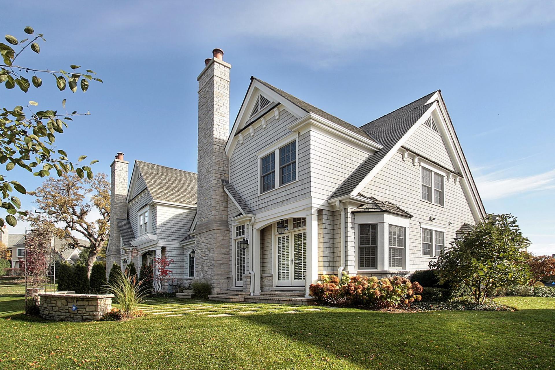 English manor inspired home with horizontal siding in a neutral tone and cedar shake roofing.