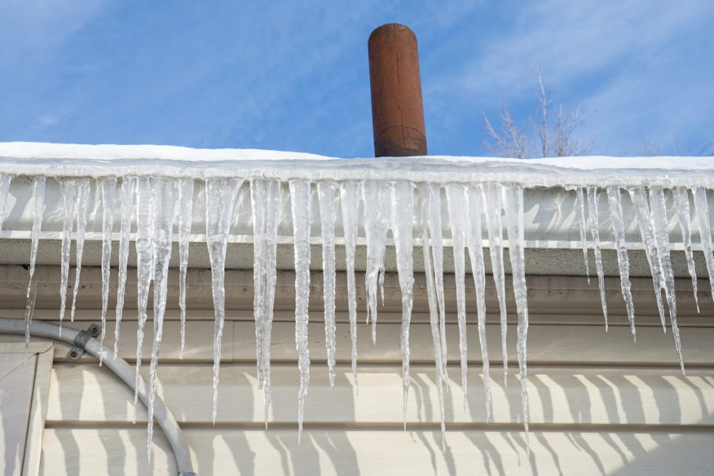 gutters have frozen and icicles hang from the gutters
