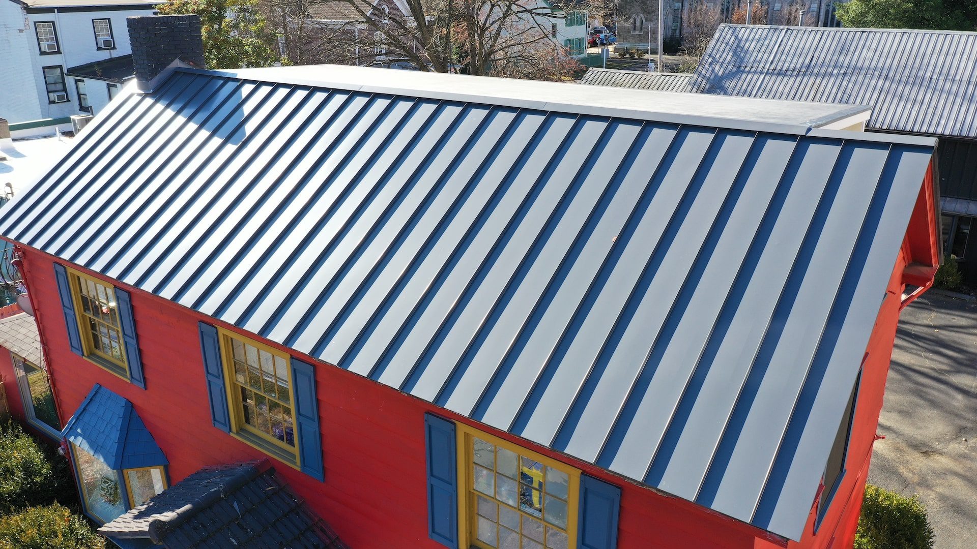 Image of a bright red building with blue metal roof installed by Alte Exteriors.
